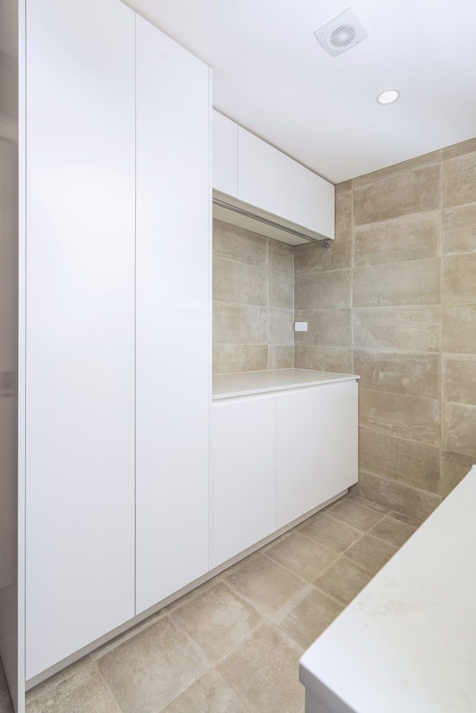 large format tiles in laundry with stone bench top and ample storage solutions in Castle Hill