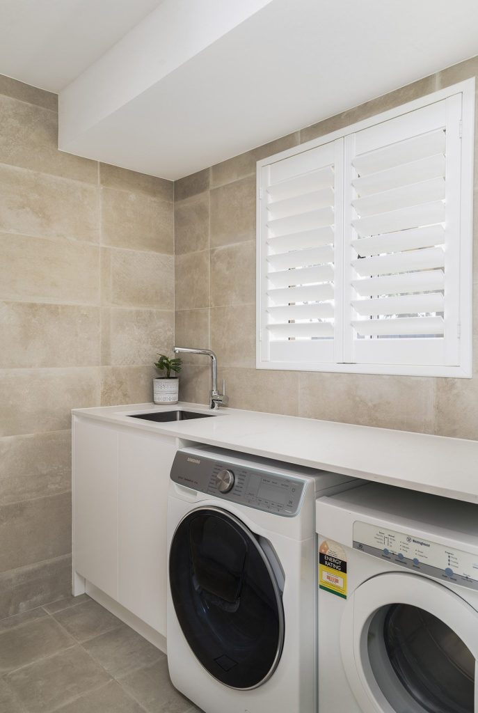 large format tiles in laundry with stone bench top and ample storage solutions in Castle Hill