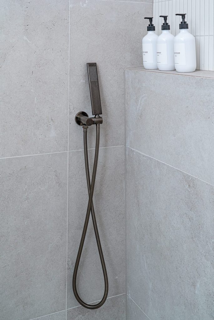 Brushed gun metal hand held shower in this modern bathroom