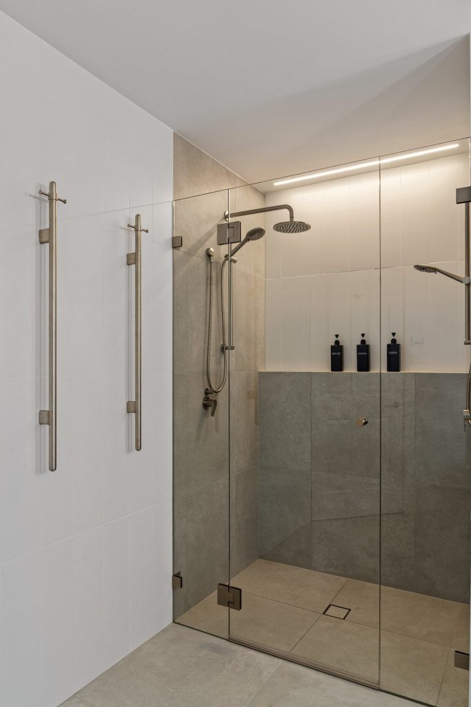 Walk-in shower with floor-to-ceiling tiling and featured recessed lighting