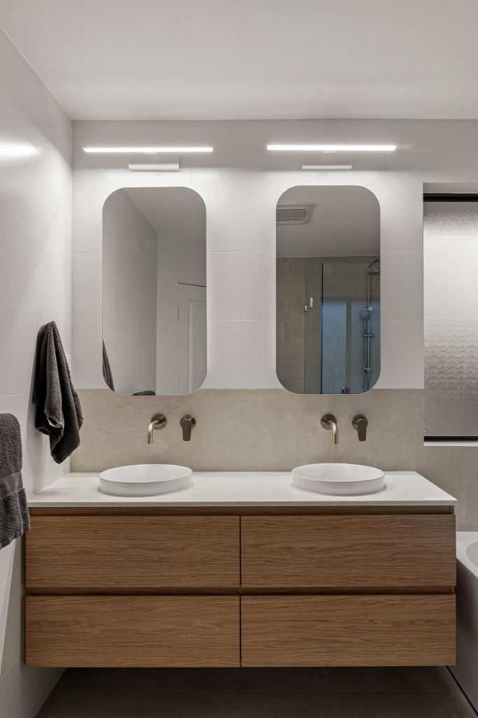 Bright bathroom featuring a floating vanity, mirrored shaving cabinets