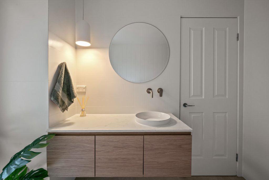 Modern bathroom featuring brushed brass tapware and designer lighting