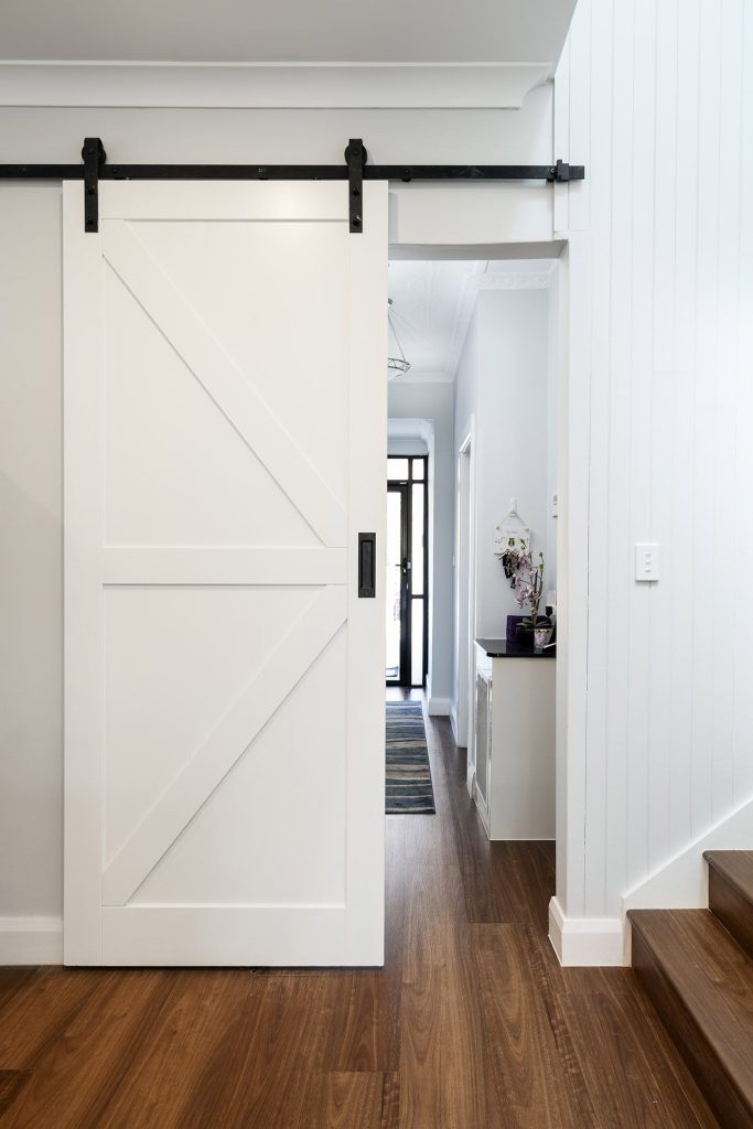 Barn door separating the existing to the new home open plan living of this First story addition built by iBuild Group in Earlwood