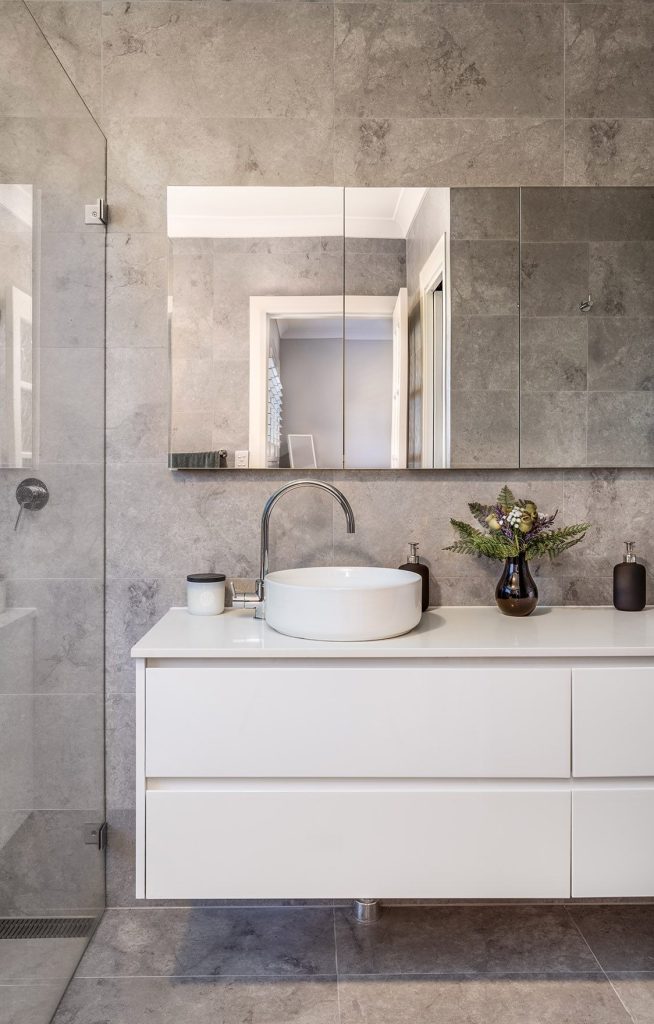 Bathroom renovation showcasing stone benchtop and mirrored cabinetry