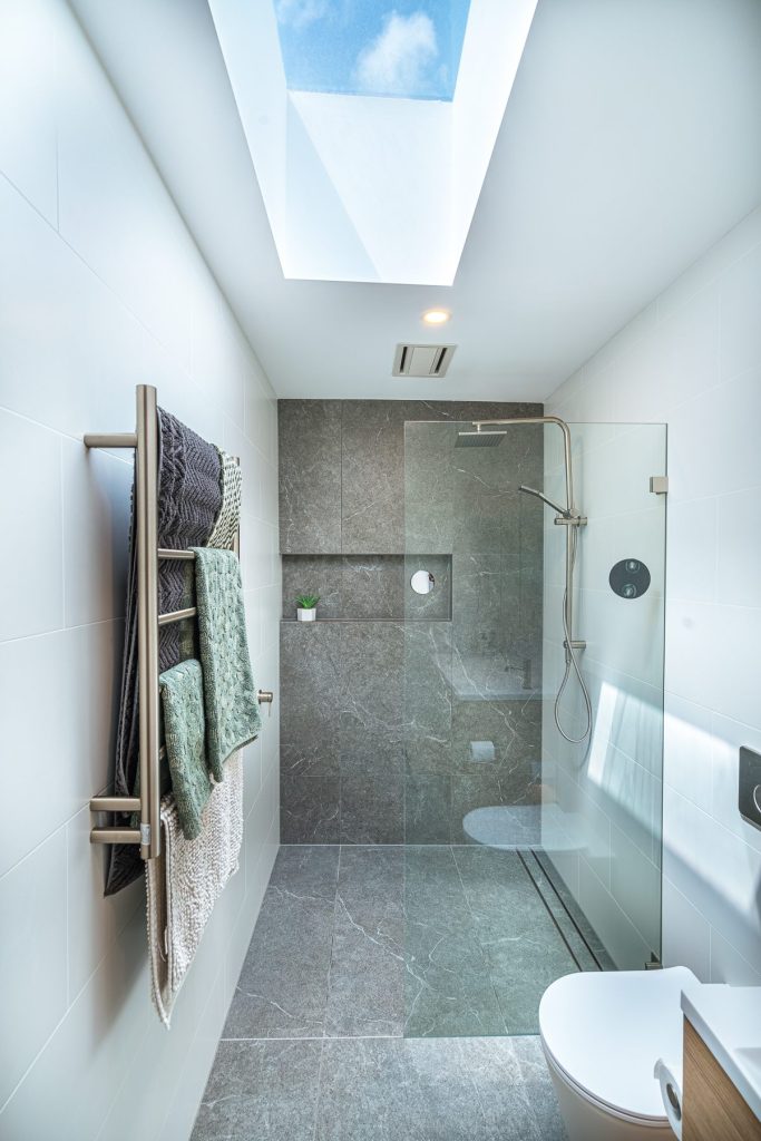 Luxury ensuite featuring floor-to-ceiling tiles and brushed nickel fixtures