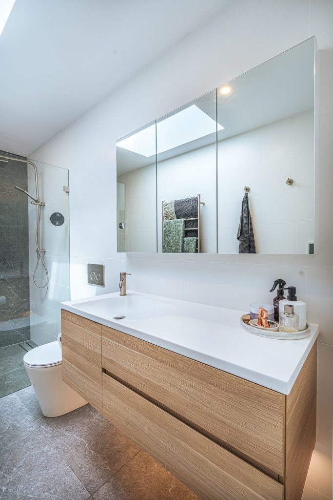 Bright bathroom featuring a floating vanity, mirrored shaving cabinet and LED lighting